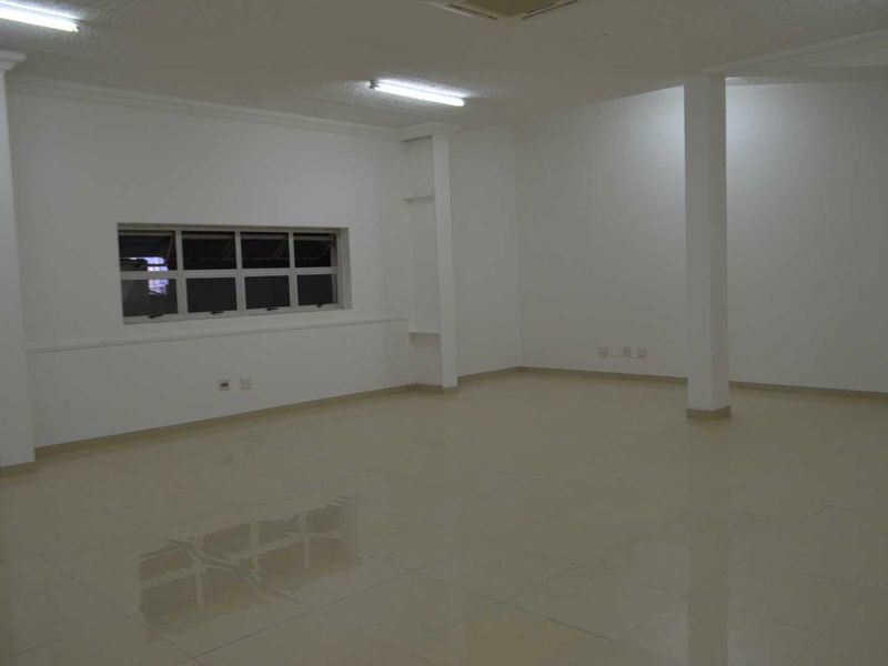 A spacious, empty open-plan area featuring tiled flooring, structural columns, and neutral white walls, suitable for various commercial or residential uses.