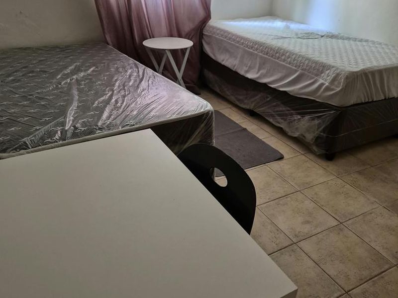 A functional bedroom featuring tiled flooring and neutral wall finishes, offering a blank canvas for potential interior updates.