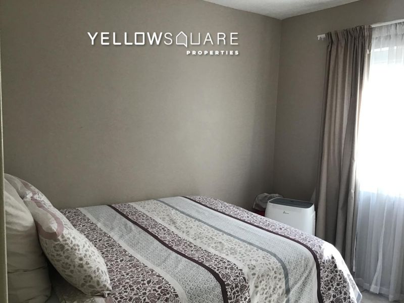 A standard bedroom featuring neutral wall tones and a window dressed with curtains, providing a simple and functional living space.