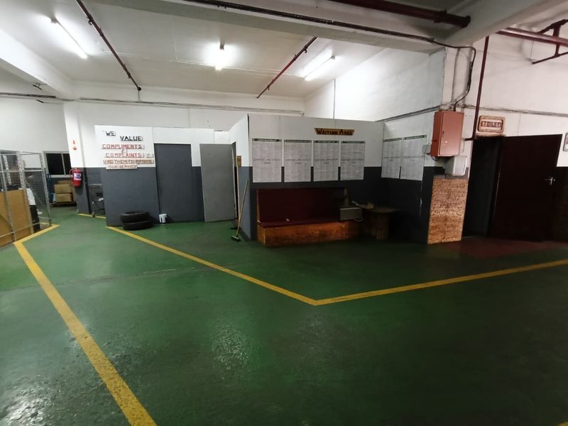 Industrial utility space featuring epoxy-coated flooring, exposed ceiling infrastructure, and partitioned waiting area with basic functional finishes.
