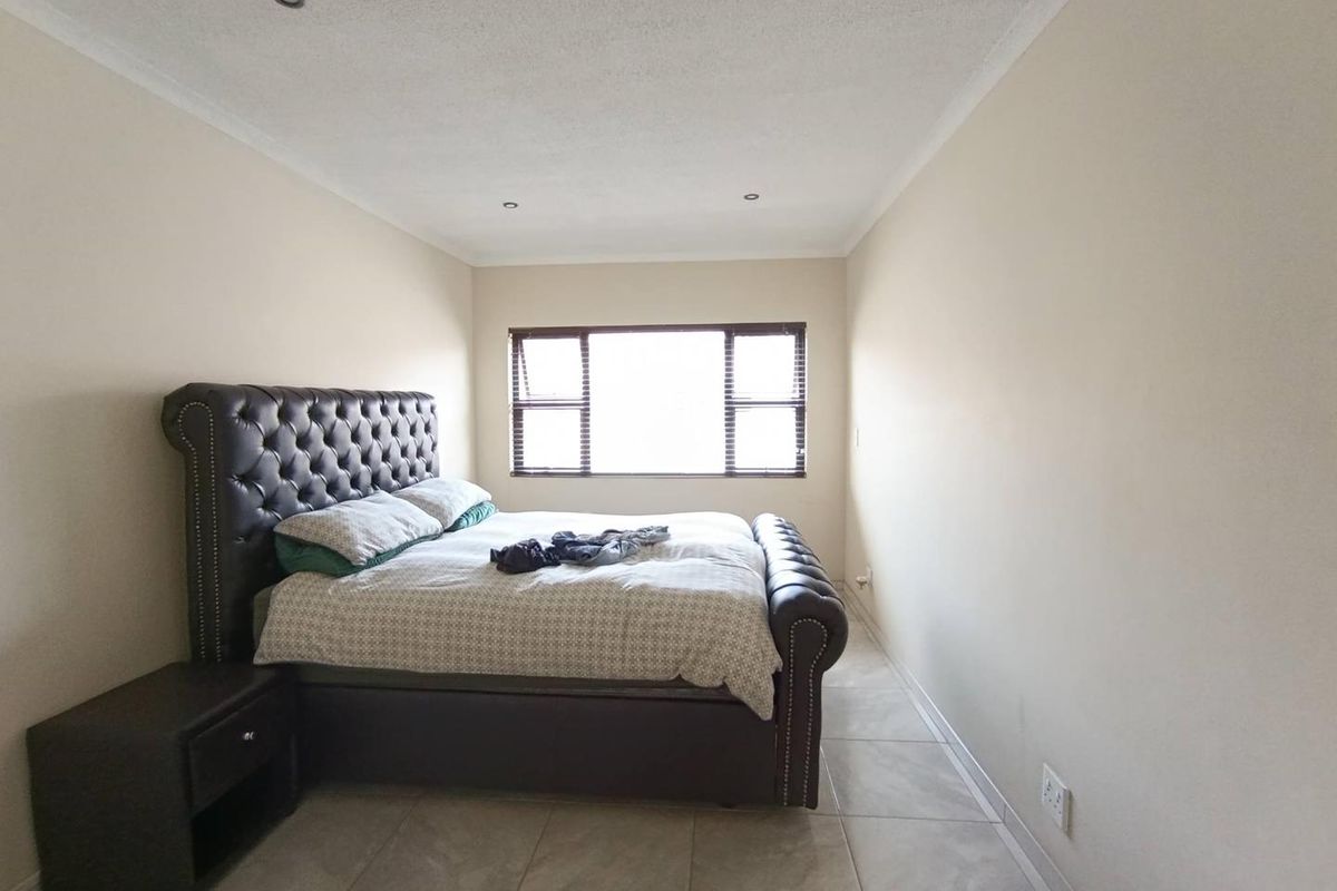 A bedroom featuring tiled flooring, recessed ceiling lighting, and a large window with fitted blinds.