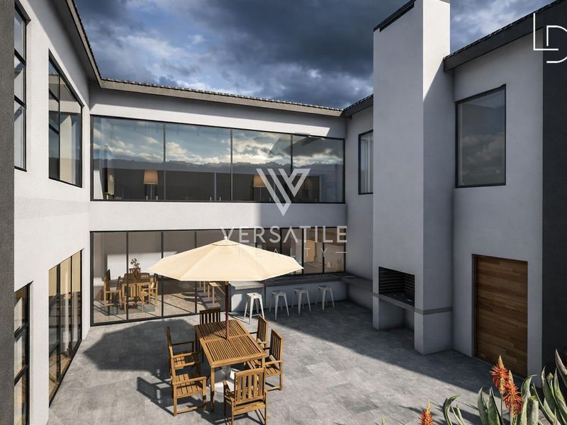 Modern outdoor patio area featuring stone paving, a built-in braai, and expansive glass doors connecting to the interior living space.