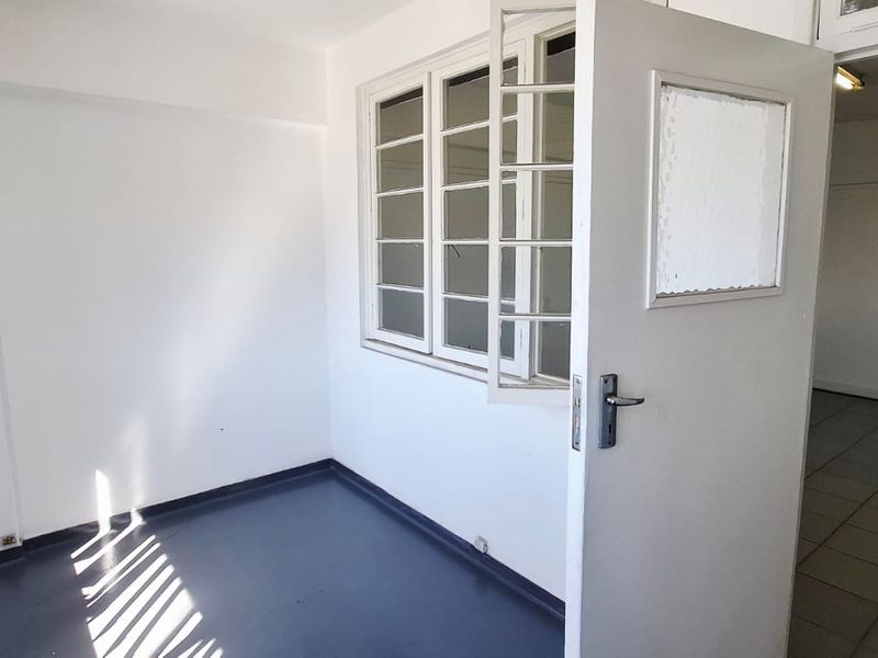 A small, vacant utility space featuring tiled flooring and a multi-pane window, providing a functional area for storage or additional workspace.