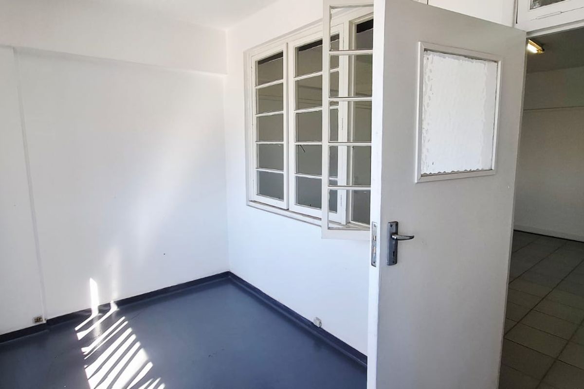 A small, vacant utility space featuring tiled flooring and a multi-pane window, providing a functional area for storage or additional workspace.