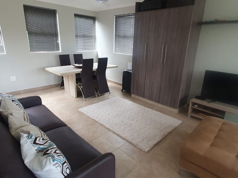 Open-plan living and dining area featuring tiled flooring, neutral walls, and built-in storage cabinetry, offering a functional and versatile space.