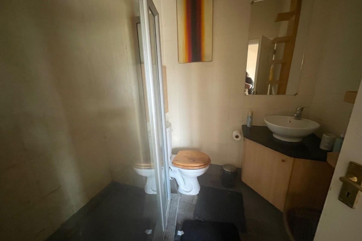 Compact bathroom featuring a glass-enclosed shower, a corner vanity with a vessel sink, and a standard toilet.