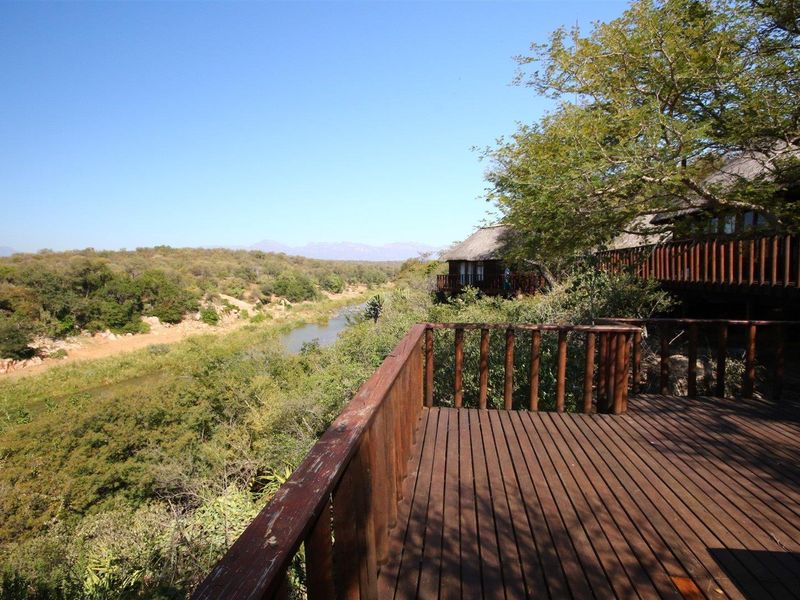 Elevated timber deck offering expansive views over the river and natural bushveld landscape, featuring a rustic timber balustrade.