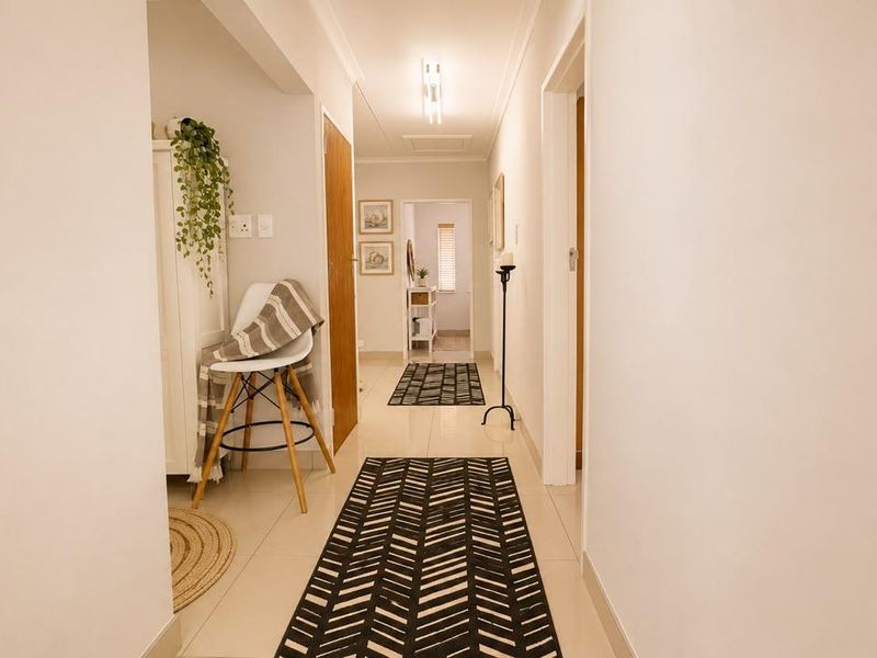 A bright and well-maintained hallway featuring neutral tiled flooring, clean white walls, and classic ceiling cornicing, providing a seamless transition between living spaces.