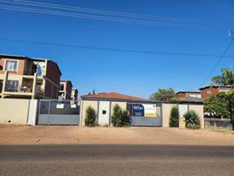 Front exterior view of the apartment complex featuring a secure gated entrance and perimeter walling.