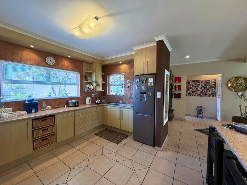 A functional kitchen featuring laminate cabinetry, tiled backsplash, and tiled flooring, offering a practical layout with ample counter space and integrated storage.