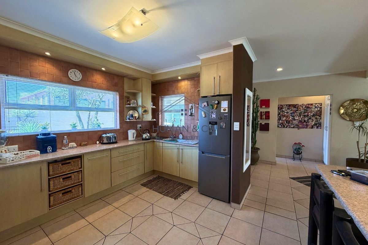 A functional kitchen featuring laminate cabinetry, tiled backsplash, and tiled flooring, offering a practical layout with ample counter space and integrated storage.