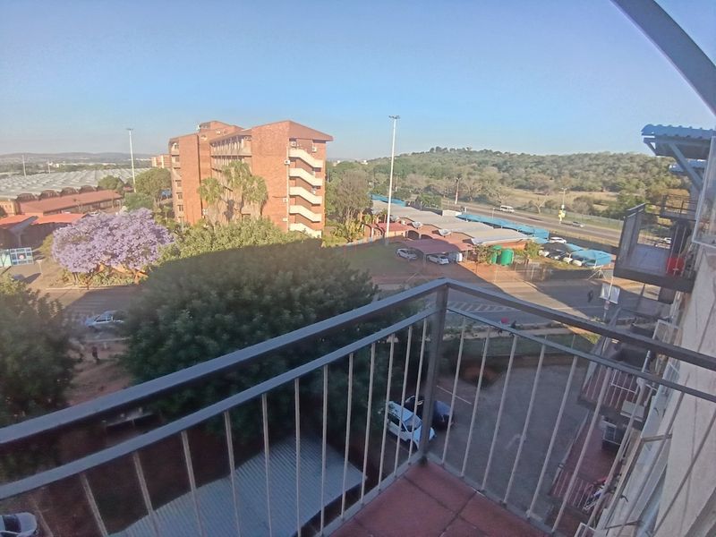 A balcony with a metal balustrade and tiled flooring, offering an elevated view of the surrounding neighbourhood and landscape.