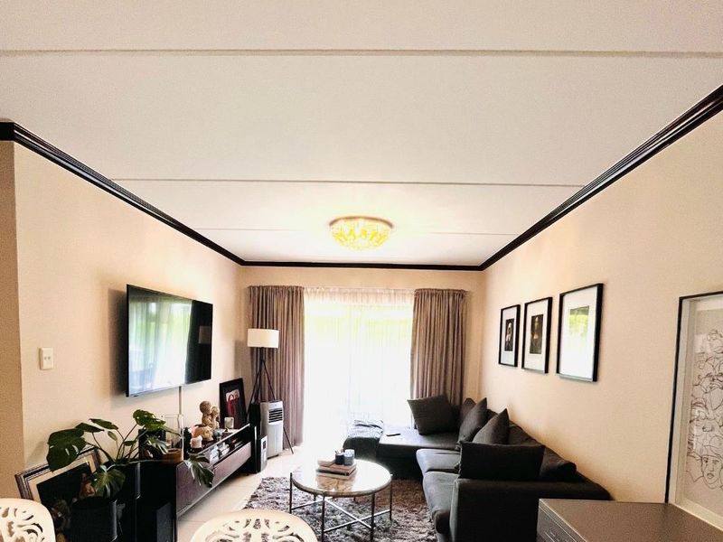 A comfortable living room featuring a ceiling cornice, central lighting, and a sliding glass door providing access to the exterior.