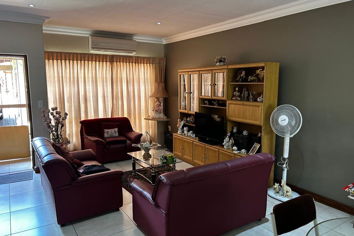 A comfortable living room featuring tiled flooring, recessed ceiling lighting, and a wall-mounted air conditioning unit, with direct access to an outdoor area.