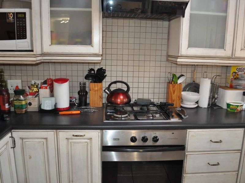 A kitchen workspace featuring a gas hob, built-in oven, extractor fan, and integrated microwave with tiled backsplash and traditional cabinetry.