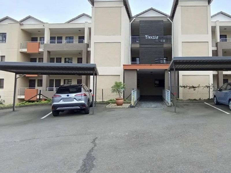 Front elevation of the Freesia apartment complex featuring covered parking bays and multi-level residential units with private balconies.