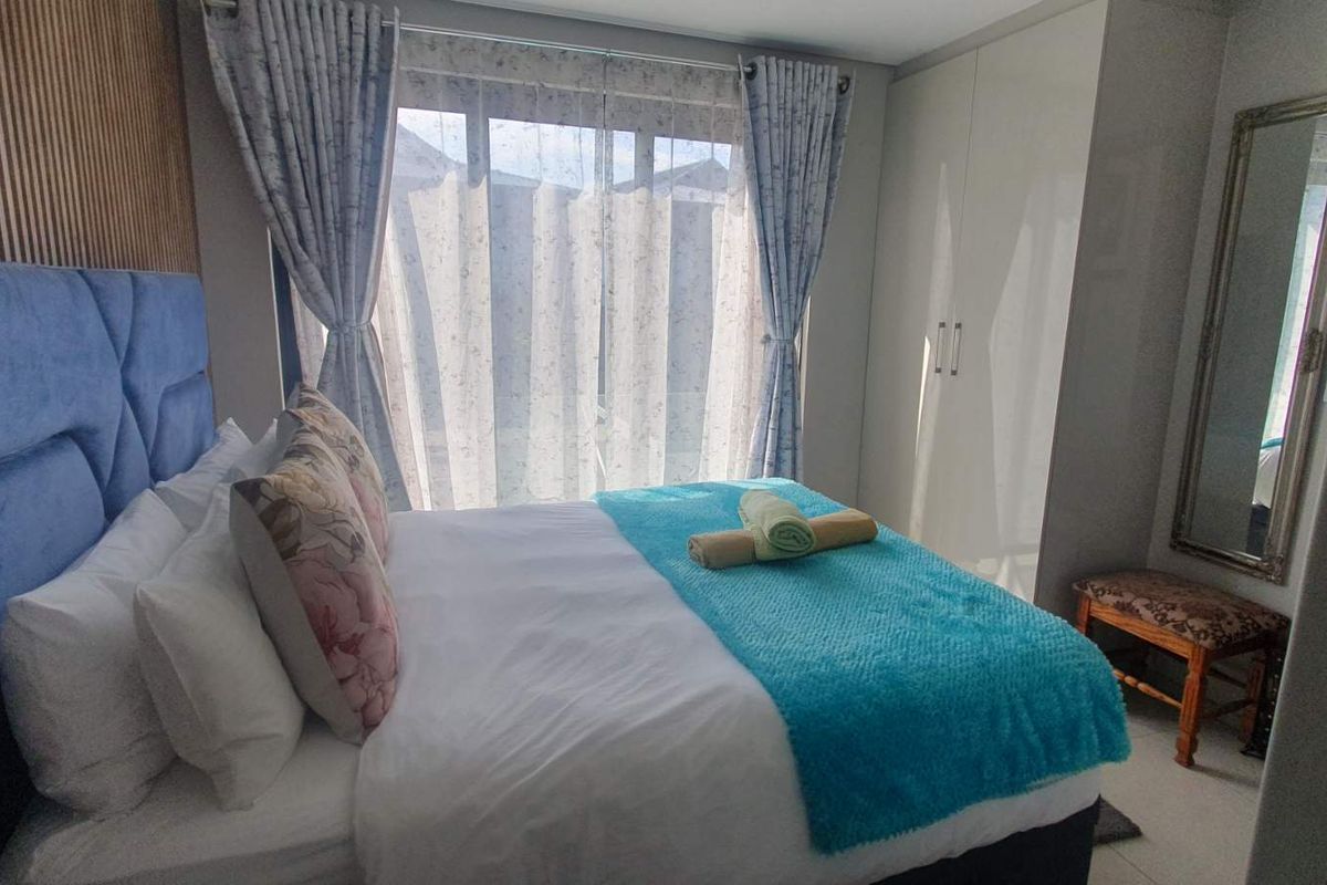 A well-maintained bedroom featuring built-in wardrobes and decorative slatted wood wall paneling, providing a clean and functional living space.