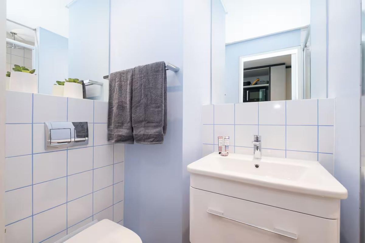A clean and functional bathroom featuring a modern vanity basin, wall-mounted toilet with concealed cistern, and tiled splashback.