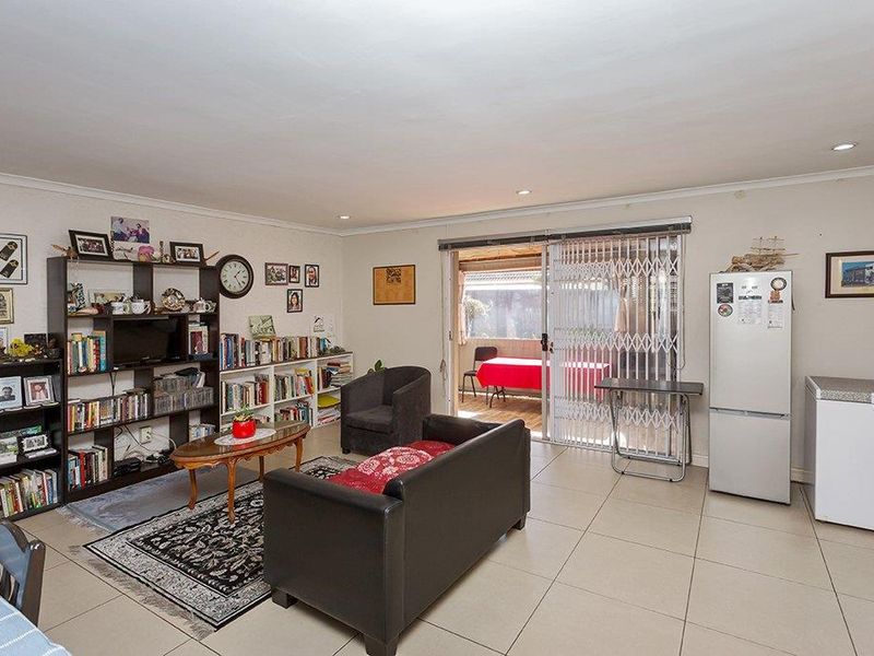 Spacious living area featuring tiled flooring, recessed downlights, and a sliding glass door providing direct access to the outdoor patio area.