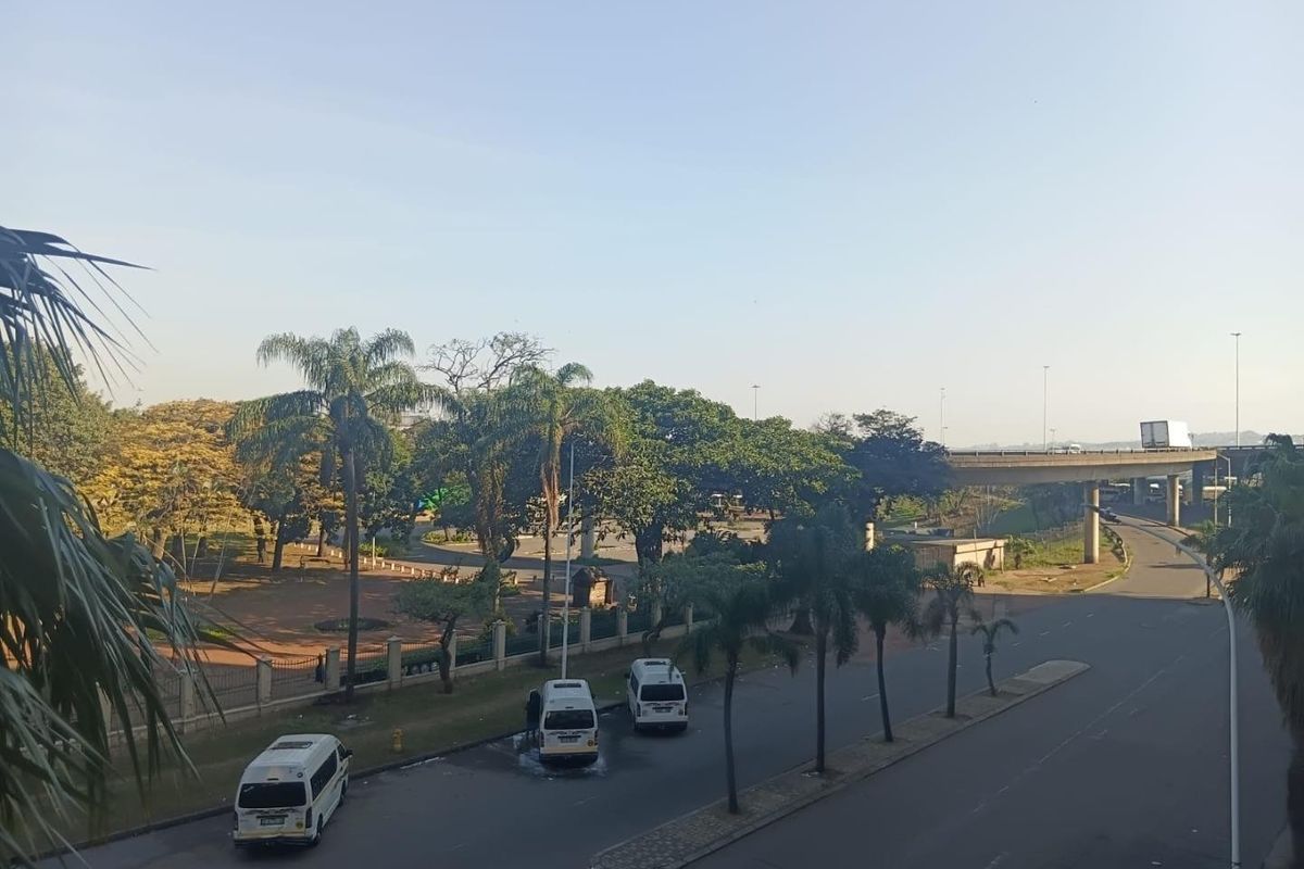 An elevated view overlooking a public park area, road, and highway overpass.