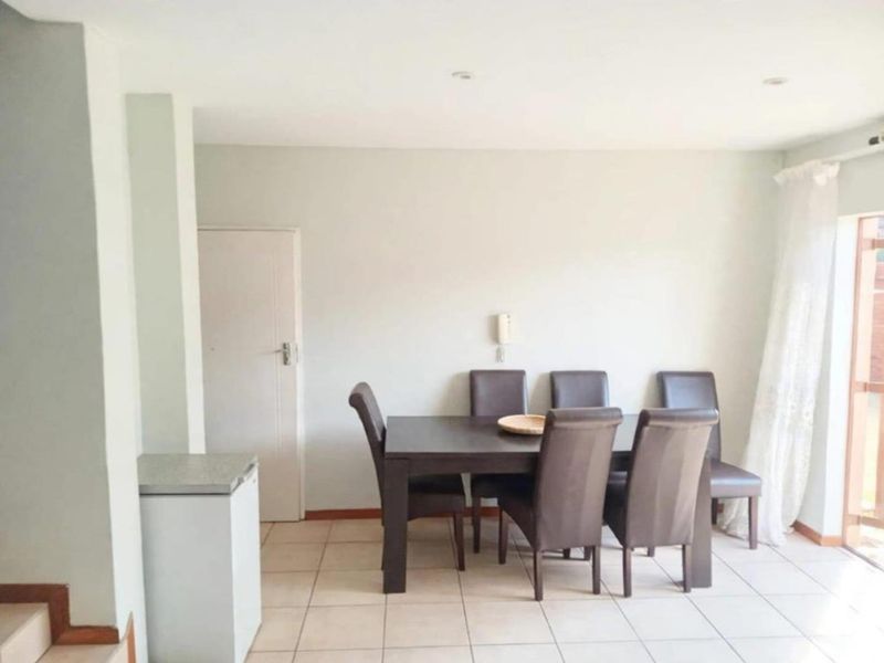 A functional dining area featuring neutral tiled flooring, recessed lighting, and an intercom system, providing a clean and simple space for meals.