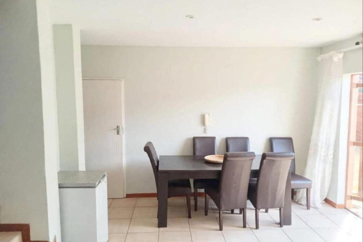 A functional dining area featuring neutral tiled flooring, recessed lighting, and an intercom system, providing a clean and simple space for meals.