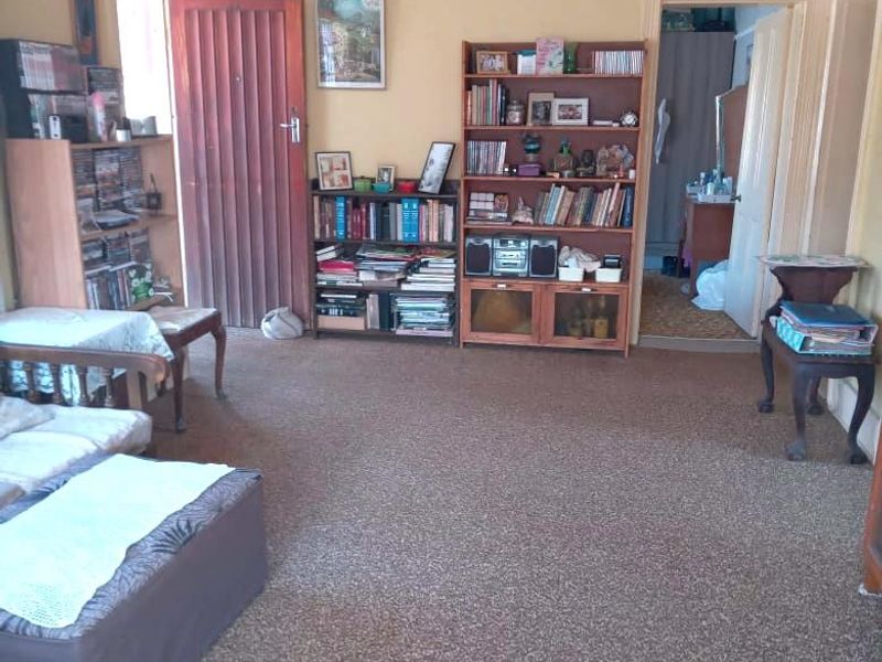 A living room featuring carpeted flooring and a coved ceiling, providing a functional space with potential for modernization and aesthetic updates.