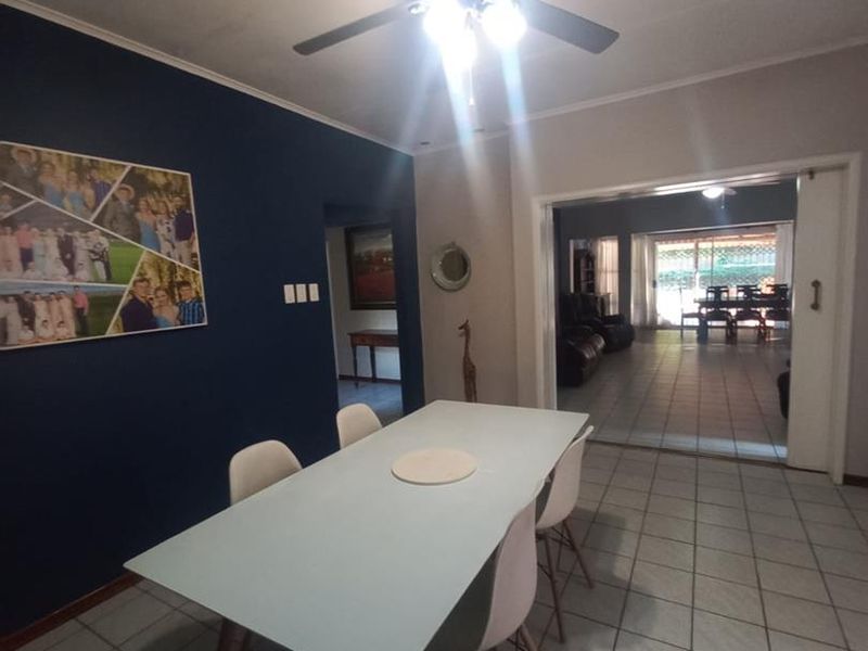 Dining room featuring tiled flooring and a ceiling fan, with an open transition to an adjacent living area through a sliding door.