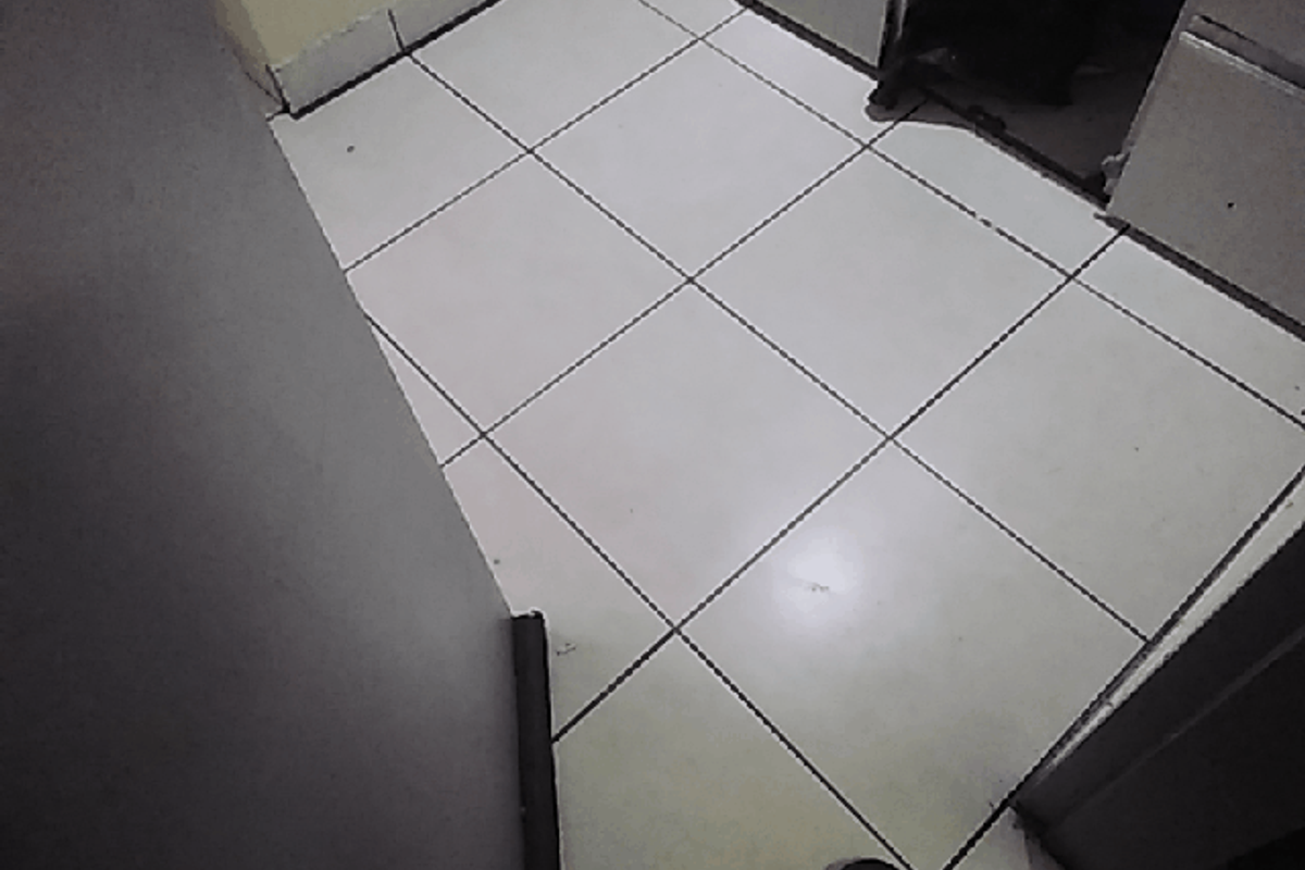 A small kitchen area featuring tiled flooring and built-in cabinetry, currently vacant and in need of cosmetic updates.