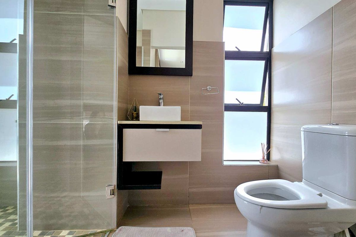 Modern bathroom featuring a floating vanity with a vessel sink, a glass-enclosed shower, and a contemporary toilet with neutral wall tiling.