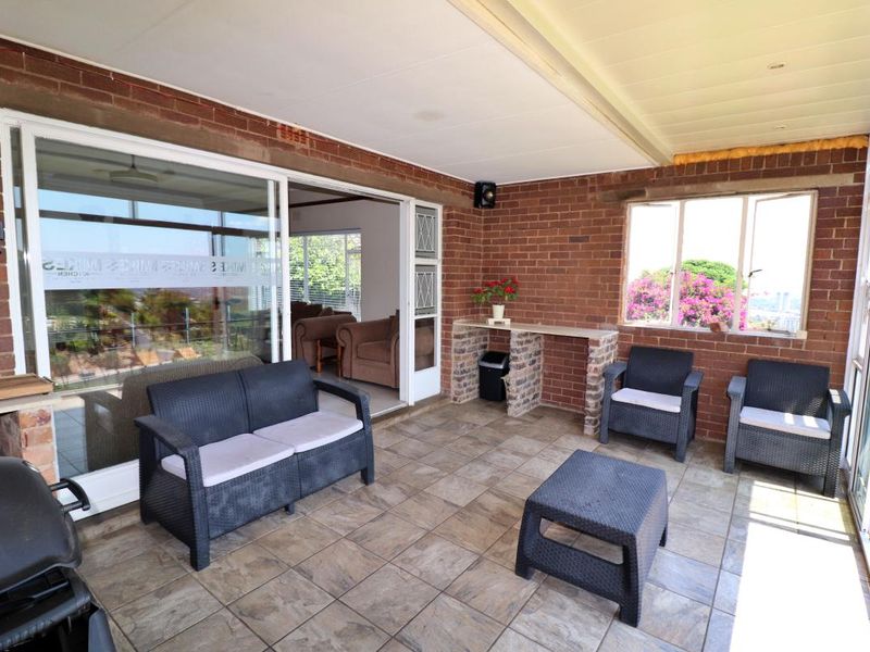 Covered patio area featuring exposed brick walls, tiled flooring, and sliding glass doors providing access to the interior living space.