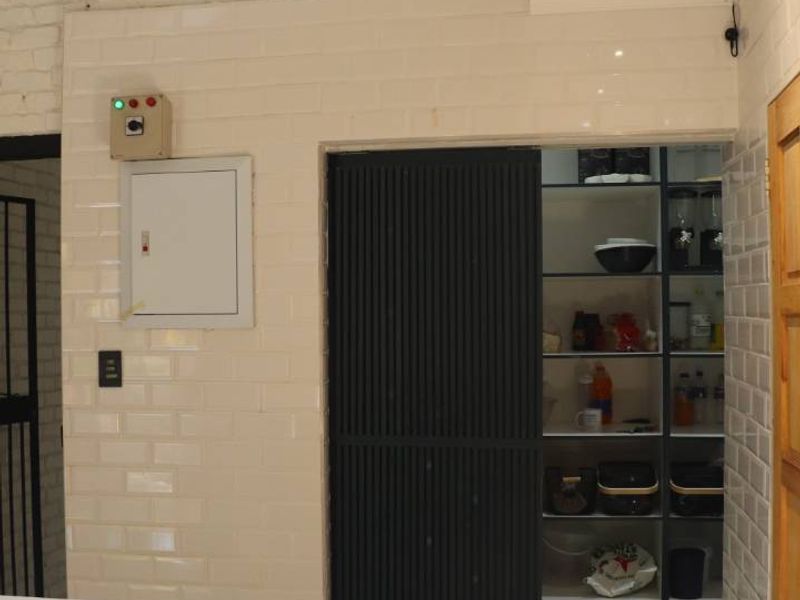 A functional scullery area featuring white subway tiles, exposed brickwork, and built-in shelving behind a modern sliding door.