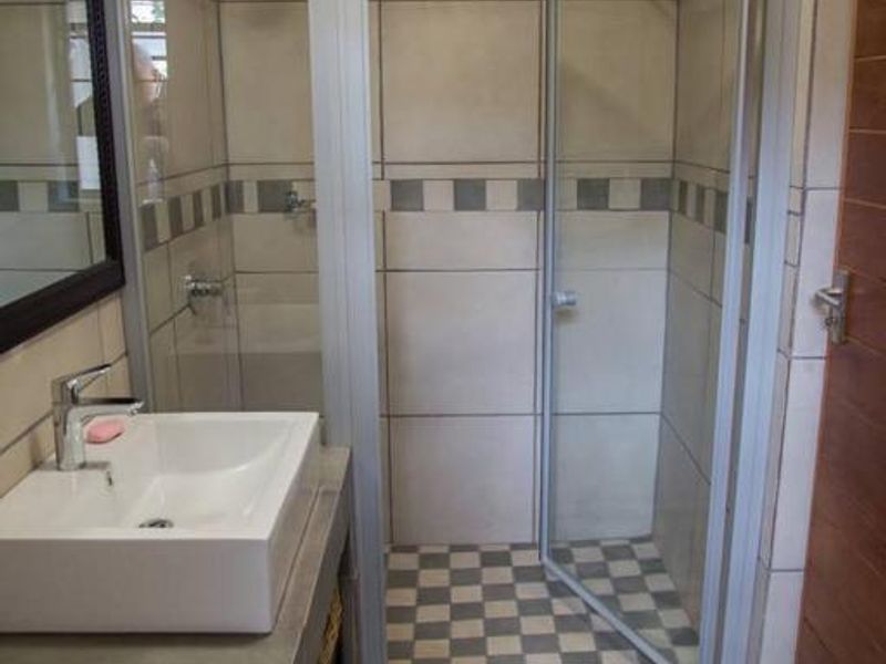 A clean, modern bathroom featuring a glass-enclosed shower, tiled walls, and a contemporary vessel sink set on a vanity counter.