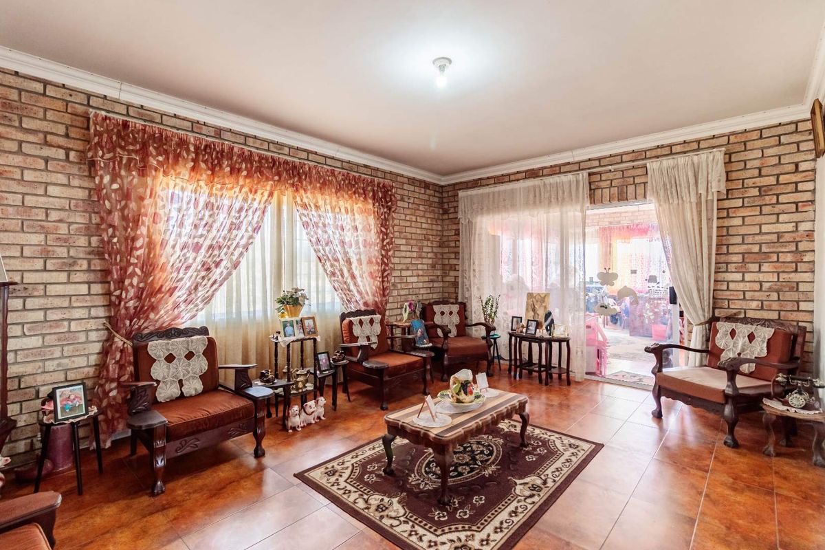 A living room featuring exposed brick walls, tiled flooring, and sliding glass doors providing access to an outdoor patio area.