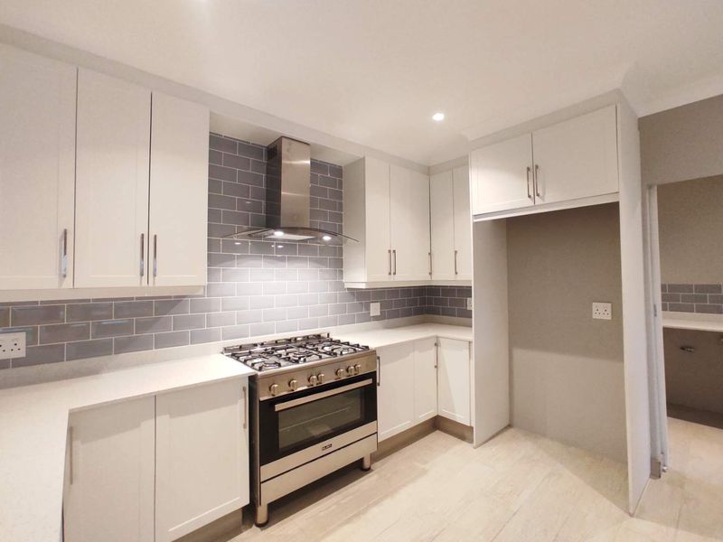 Modern kitchen featuring white cabinetry, quartz countertops, subway tile backsplash, and stainless steel gas oven with extractor fan.