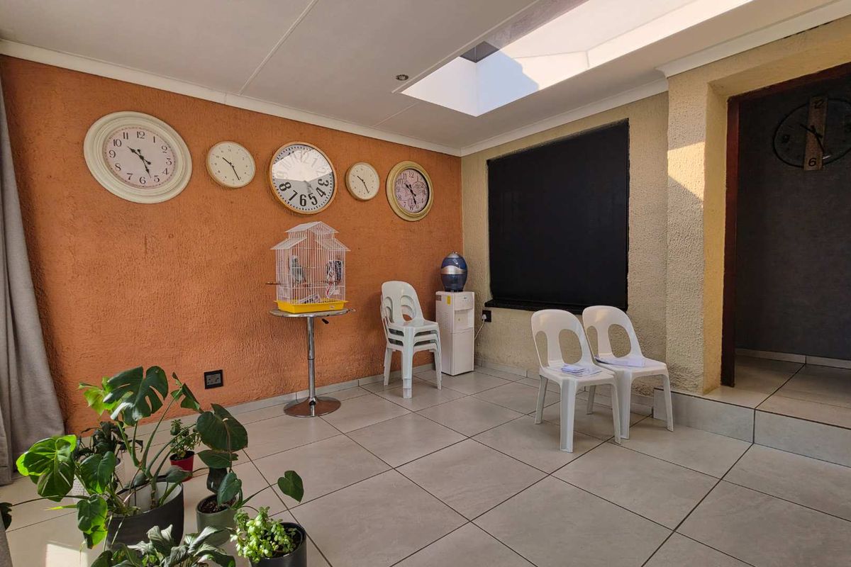 A bright living area featuring tiled flooring, a skylight, and textured wall finishes, offering a versatile space for relaxation or casual seating.
