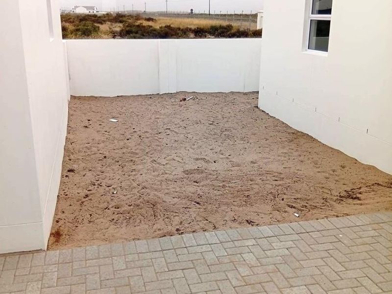 A rear courtyard area featuring paved patio space and an unlandscaped garden enclosed by boundary walls.