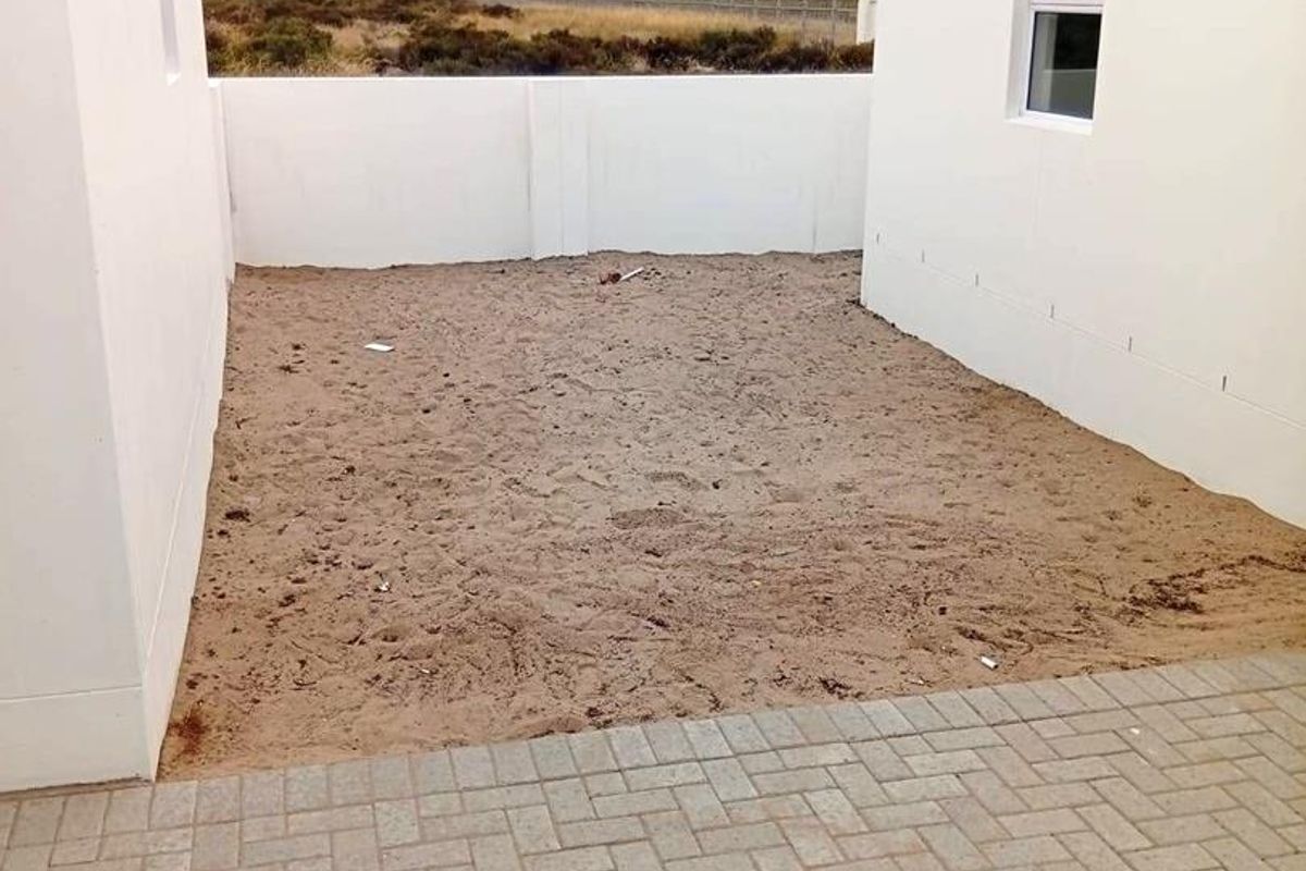 A rear courtyard area featuring paved patio space and an unlandscaped garden enclosed by boundary walls.
