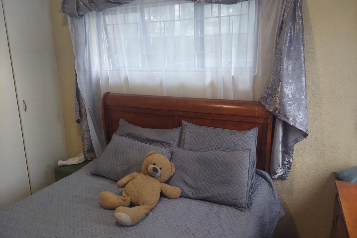 A bedroom featuring a built-in wardrobe and a window fitted with security bars.