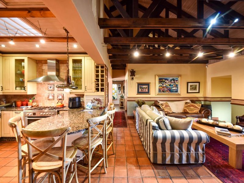 Spacious open-plan kitchen and living area featuring exposed timber beams, terracotta flooring, granite countertops, and a well-equipped kitchen with a gas stove.