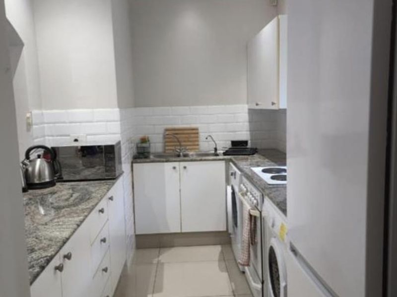 A compact, well-maintained kitchen featuring granite countertops, white cabinetry, subway tile backsplash, and integrated appliance spaces with modern recessed lighting.