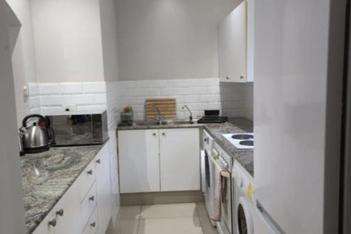 A compact, well-maintained kitchen featuring granite countertops, white cabinetry, subway tile backsplash, and integrated appliance spaces with modern recessed lighting.