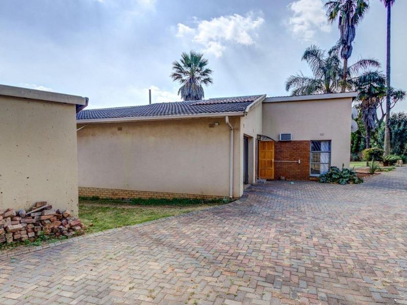 Exterior view of the property featuring a paved driveway, brick and rendered facade, tiled roof, and an installed air conditioning unit.