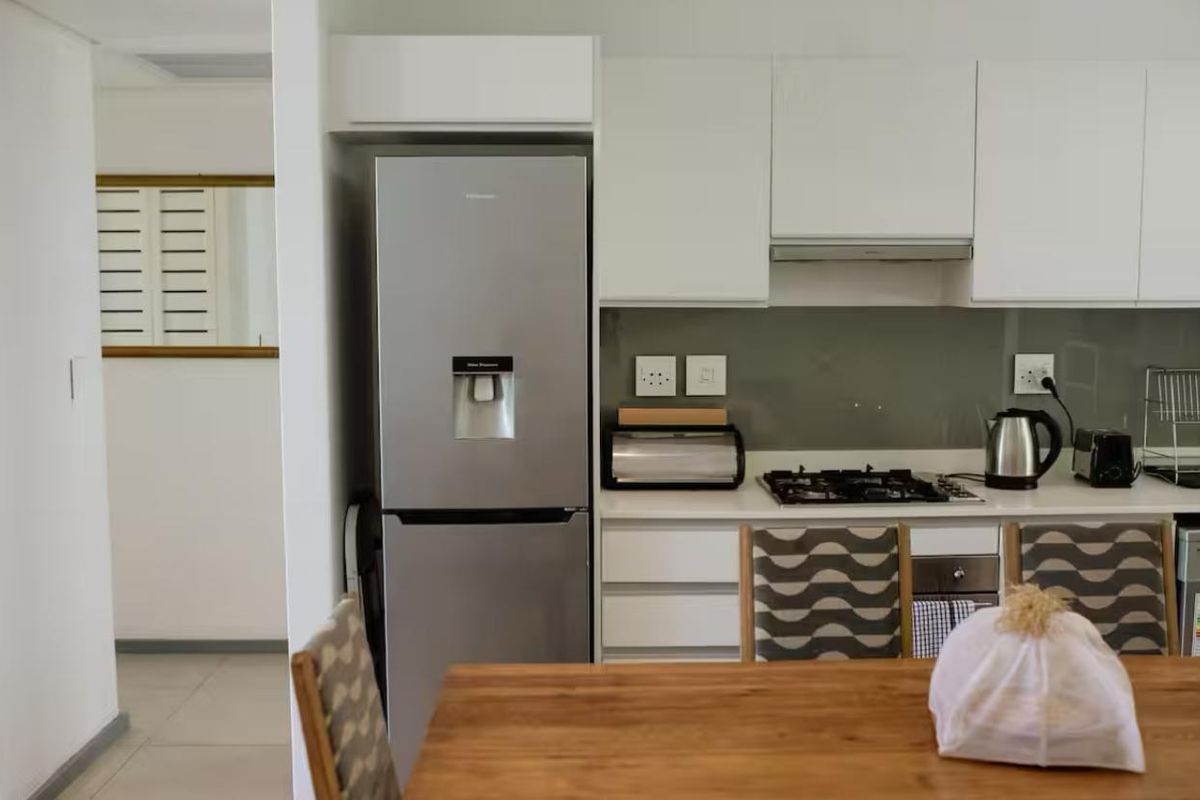 Modern kitchen featuring white cabinetry, stone countertops, a gas hob, and integrated extractor fan, offering a clean and functional cooking space.