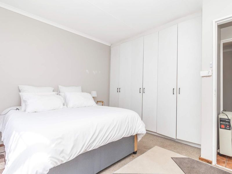 A bedroom featuring neutral walls, carpeted flooring, and extensive built-in white cabinetry for storage.