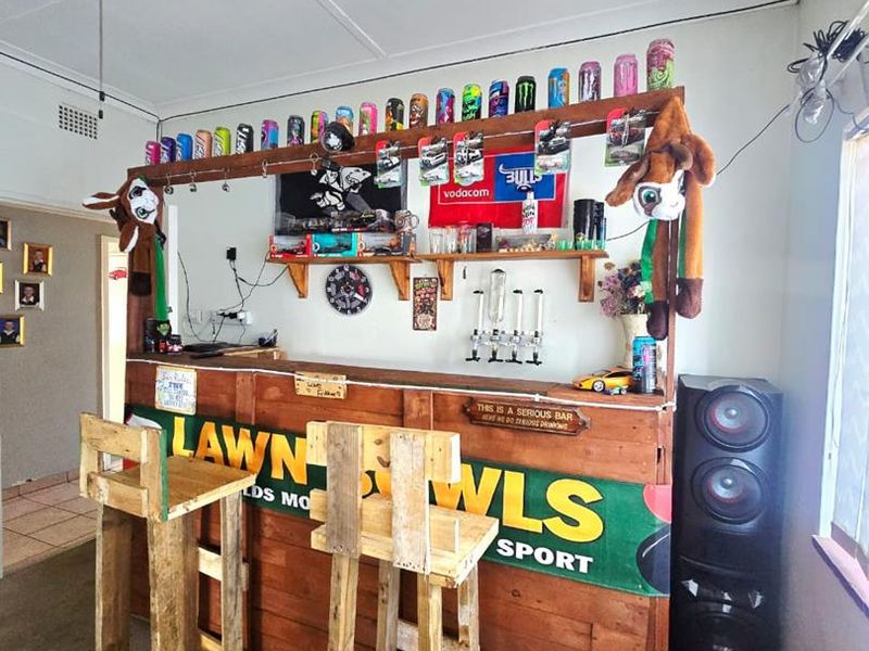 A home bar area featuring a custom-built wooden bar counter and a ceiling fan, providing a dedicated space for entertainment.