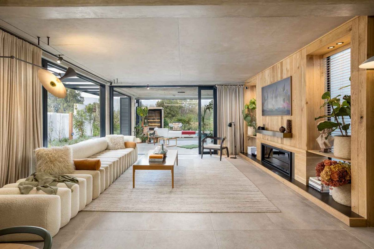 Modern living room featuring timber wall paneling, a built-in fireplace, concrete ceiling, and large sliding glass doors opening to an outdoor patio area.