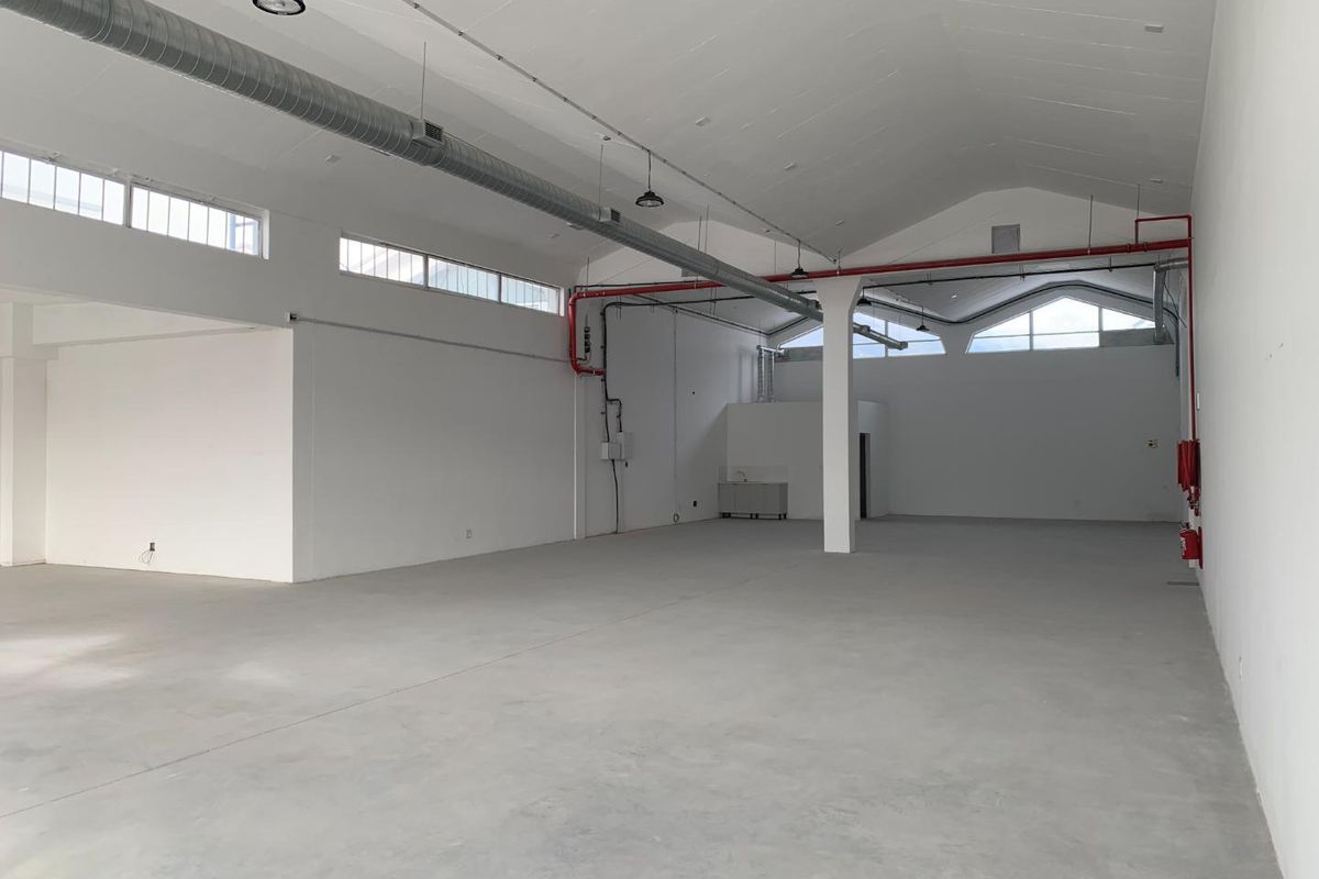 Spacious open-plan retail or industrial unit featuring high vaulted ceilings, exposed ductwork, polished concrete floors, and abundant natural light from clerestory windows.