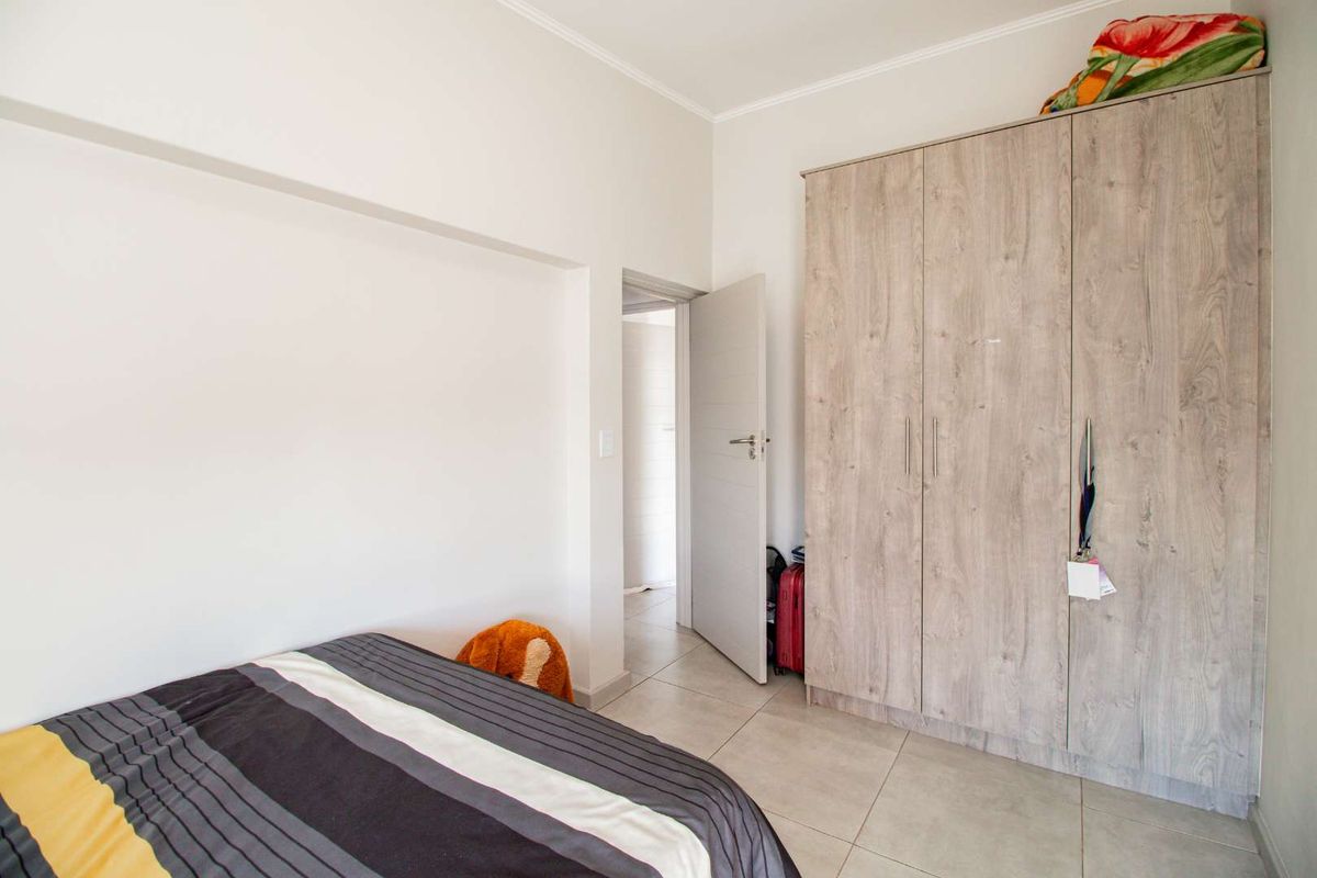 A bedroom featuring neutral tiled flooring and built-in wood-grain cabinetry, providing ample storage space and a clean, functional layout.