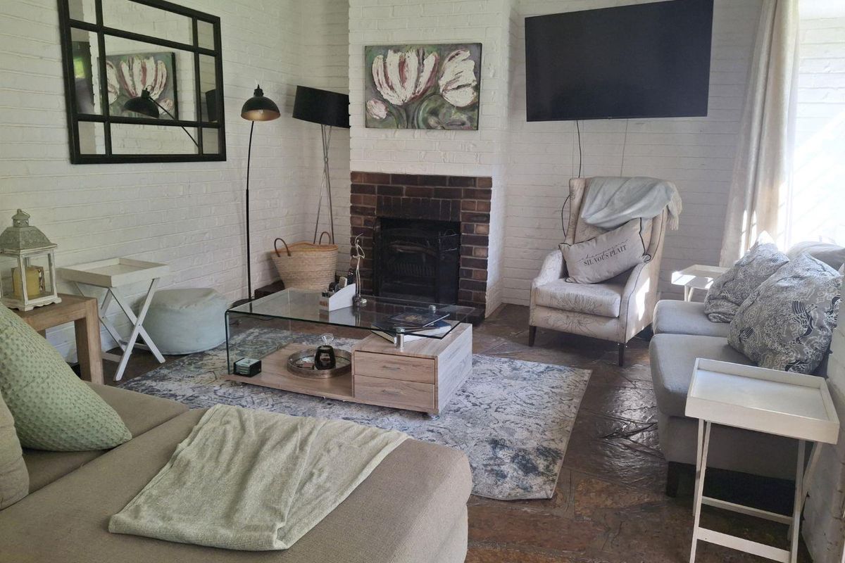 Cozy living room featuring a classic brick fireplace, painted brick walls, and rustic stone flooring, creating a warm and inviting atmosphere.